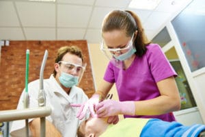 child dentist treat boy teeth under sedation with dental curing ultraviolet light equipment